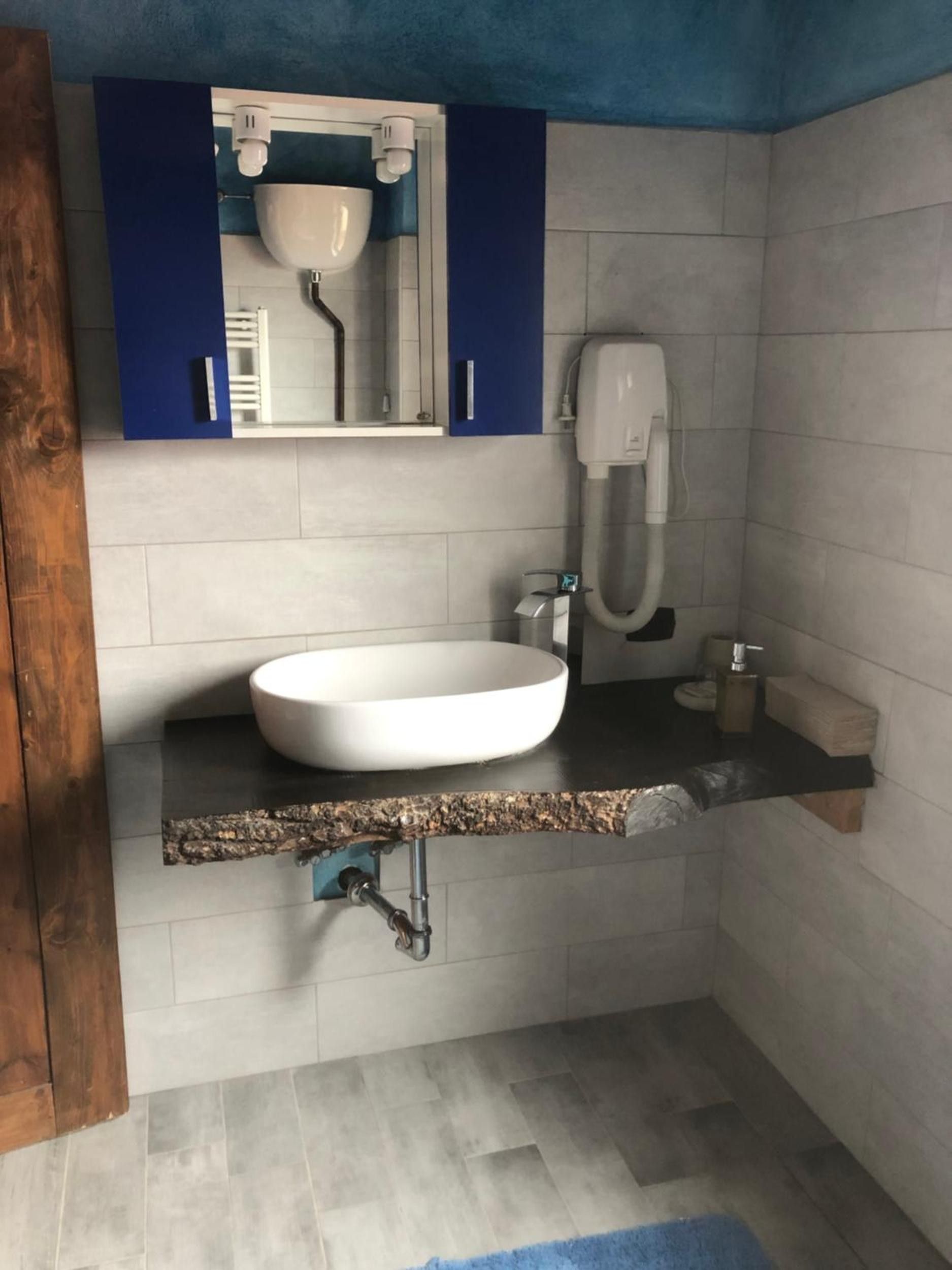 Un baño con lavamanos blanco, armarios azules, un perchero y una alfombra azul.