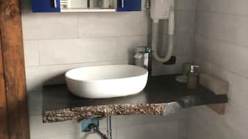 Un baño con lavamanos blanco, armarios azules, un perchero y una alfombra azul.