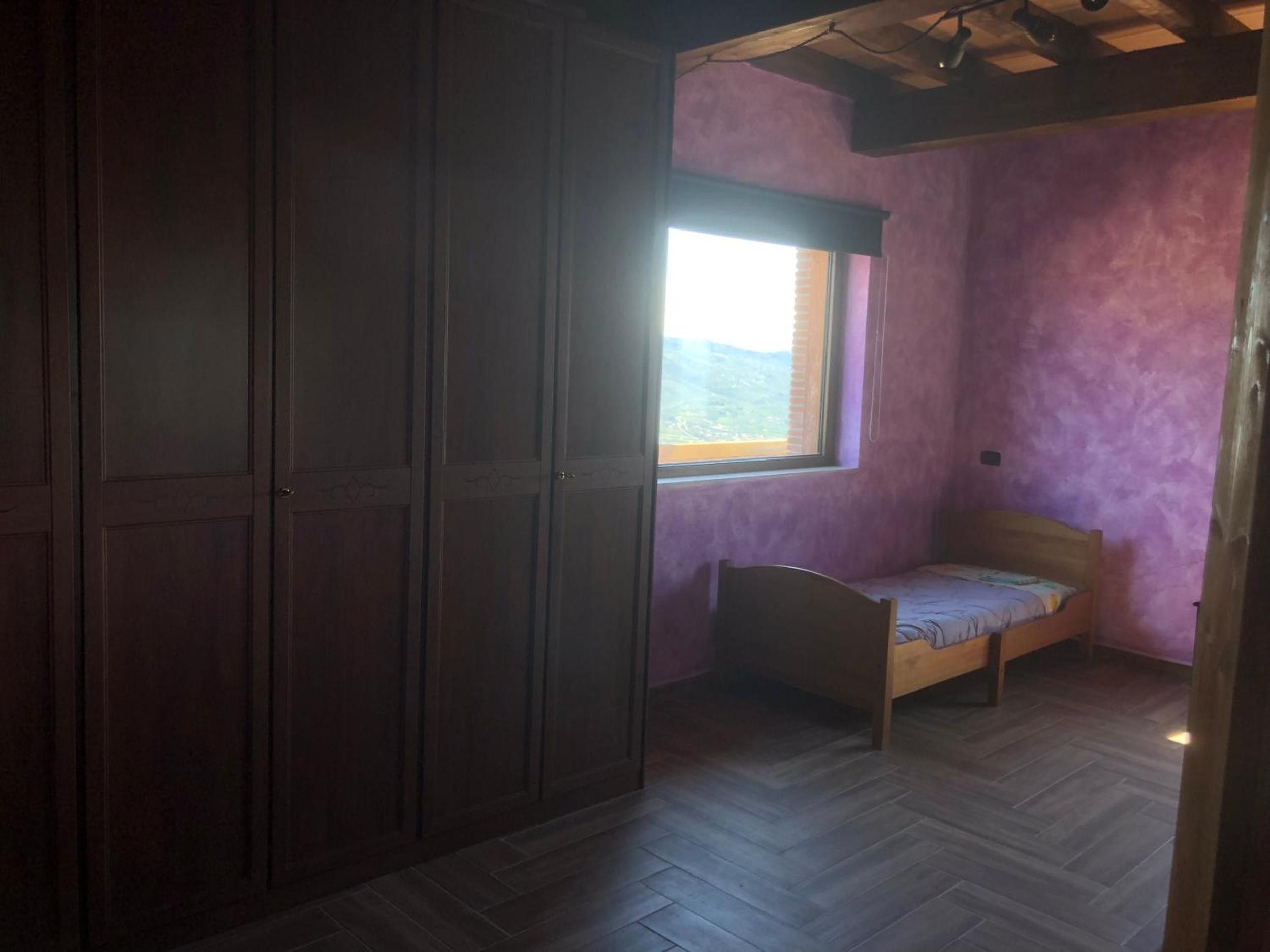 Une chambre avec une armoire en bois, un lit simple et une fenêtre donnant sur un beau paysage.