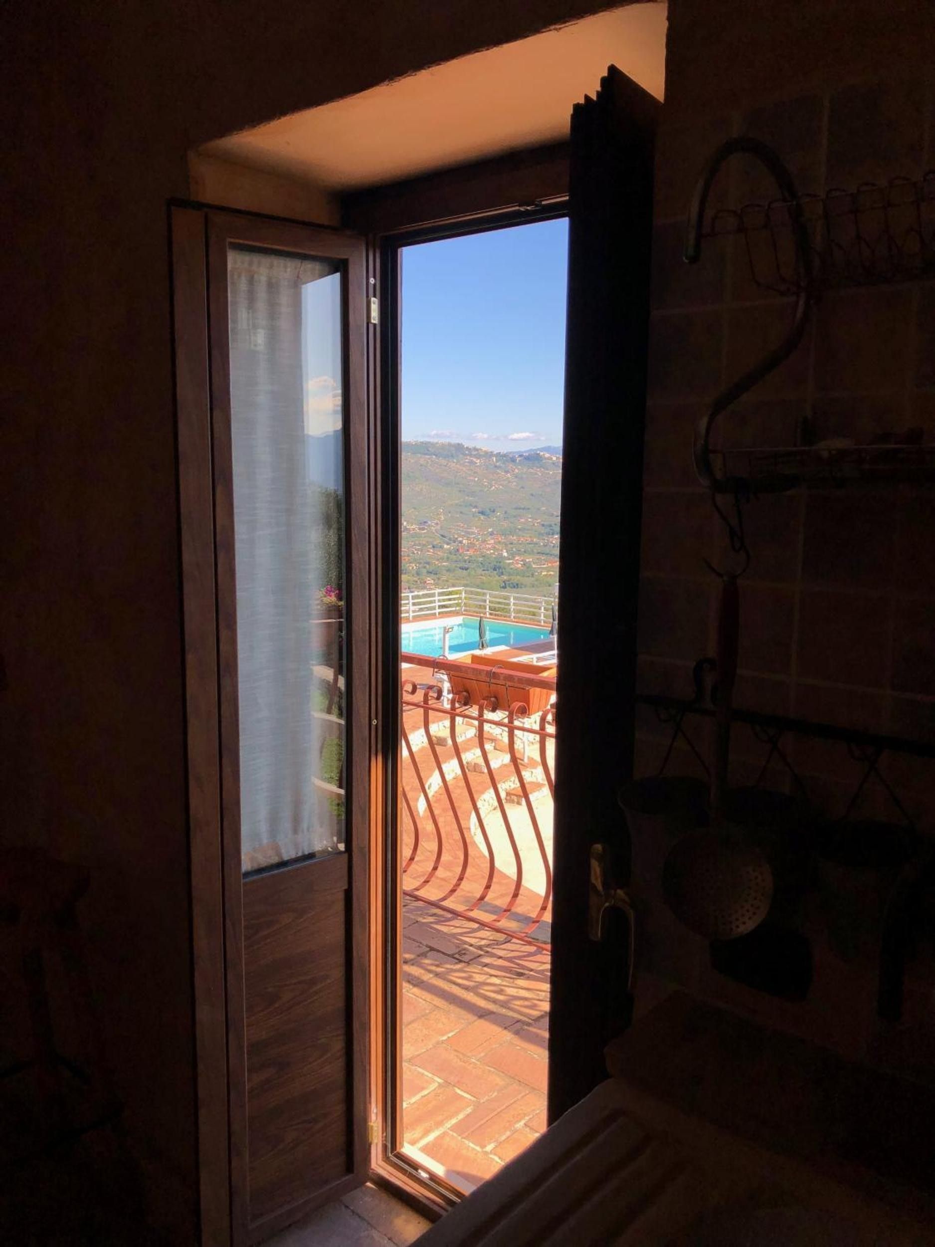 Ein Zimmer mit einer Schiebeglastür, die auf einen Balkon mit Blick auf ein Schwimmbad und Berge führt.