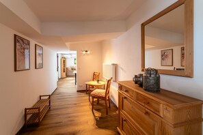 Ein Flur mit Holzboden, einem Holzschrank, einem Stuhl, einem Tisch und gerahmten Bildern an den Wänden.