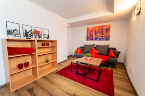 Ein modernes Wohnzimmer mit einem Bücherregal aus Holz, einem roten Sofa und einem Couchtisch.