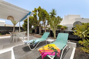 A patio area with two lounge chairs, a table, and a pergola. - Paraiso Marino by Escape Home (Puerto del Carmen)