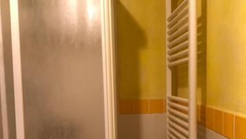 A bathroom with a white door, a white radiator, and yellow and white tiled walls.