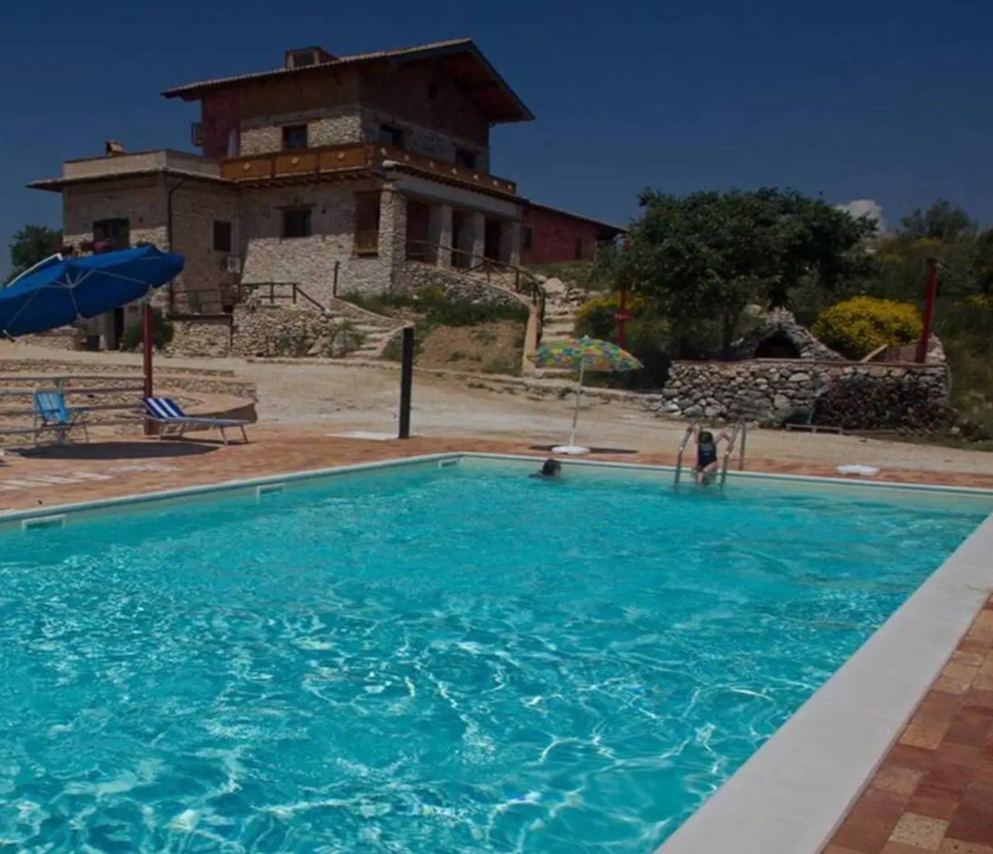 A swimming pool with a stone wall and a building in the background.