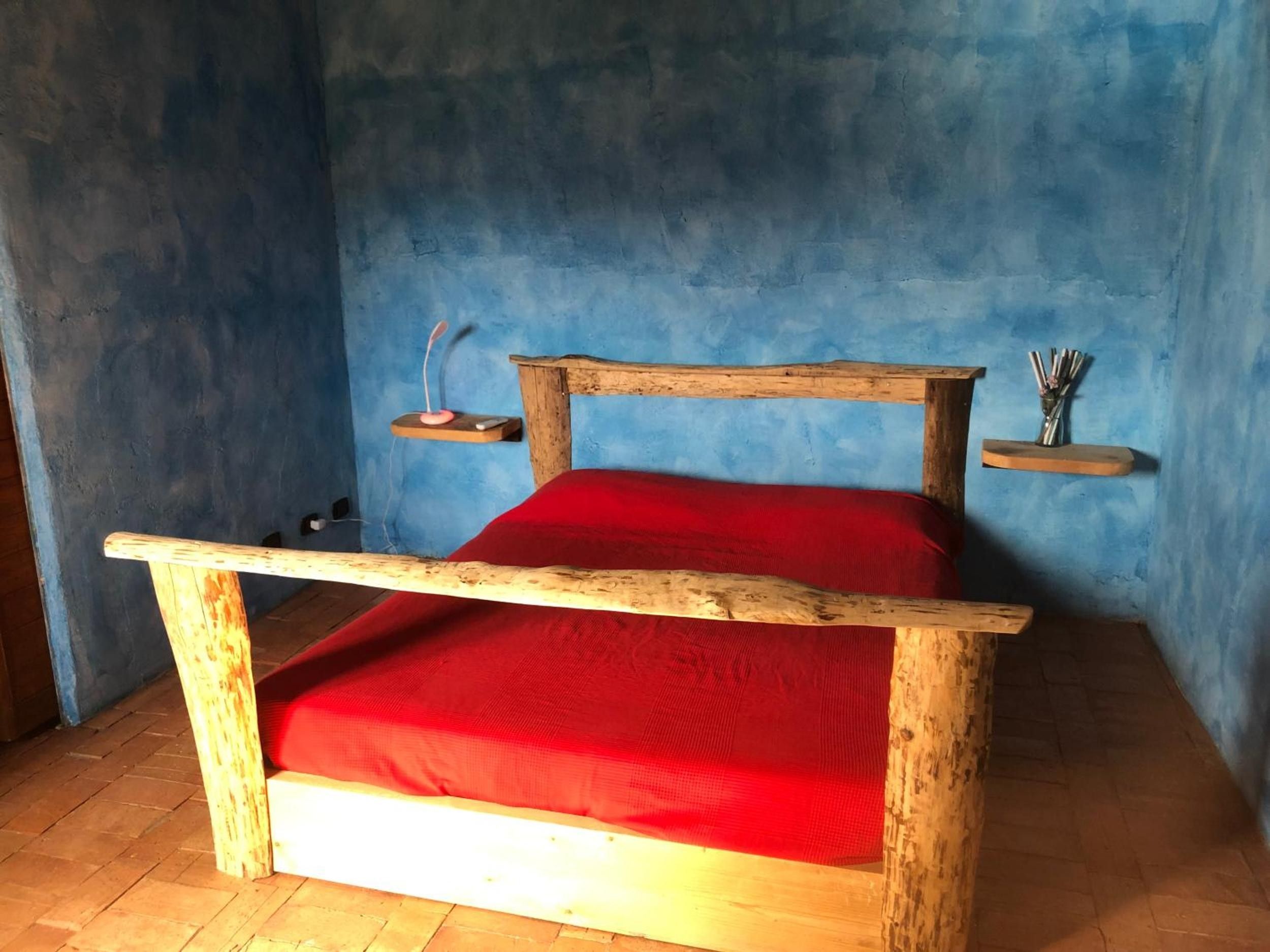 A wooden bed with a red mattress in a room with blue walls.