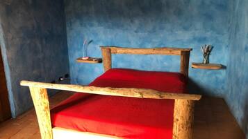 A wooden bed with a red mattress in a room with blue walls.