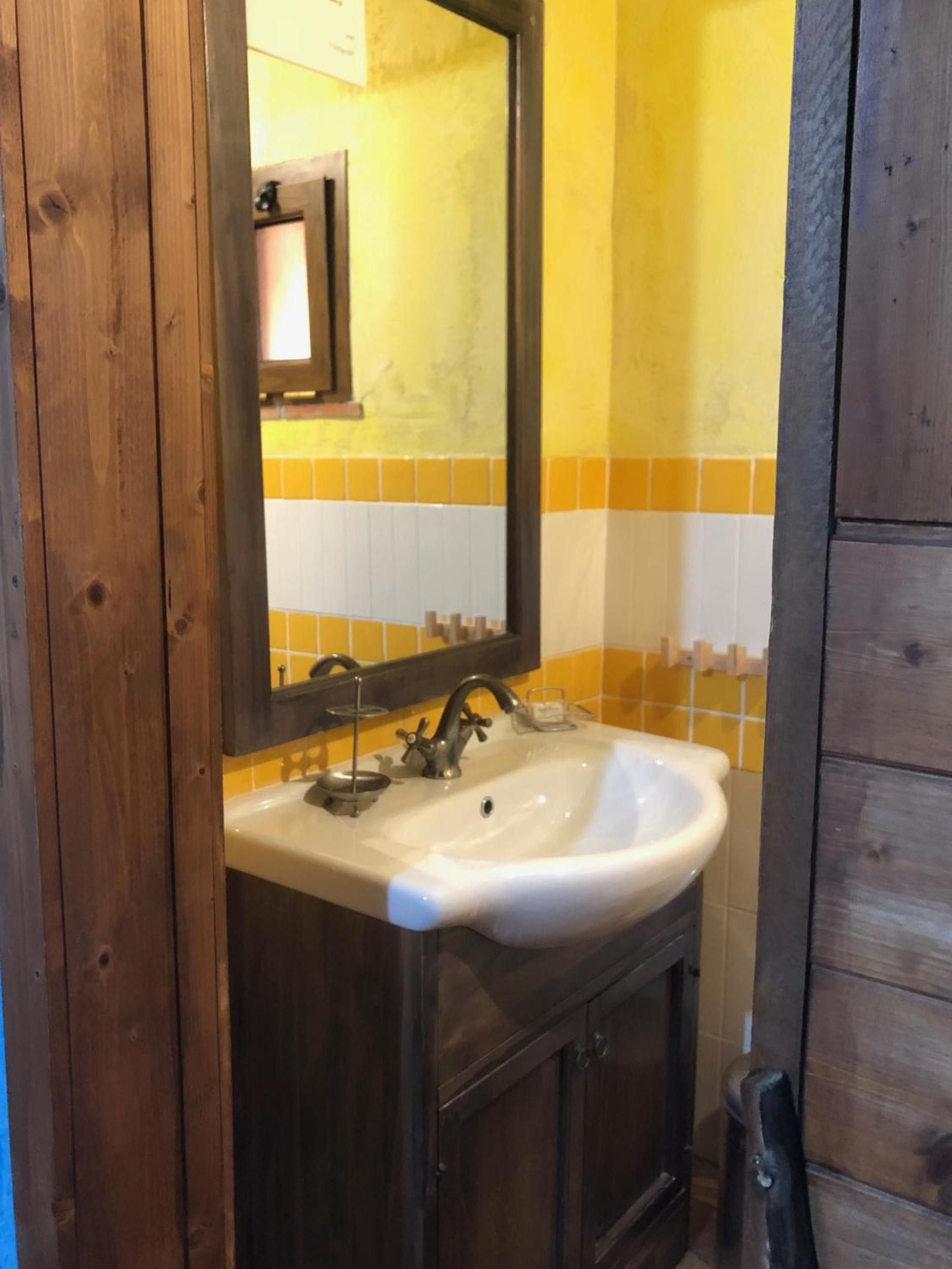 Un baño con tocador de madera, lavamanos blanco y espejo.