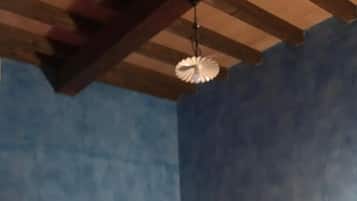 Ein Zimmer mit einem Bettgestell aus Holz, einer roten Matratze und einer Hängeleuchte.