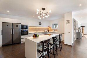 A modern kitchen with a central island, stainless steel appliances, and a contemporary light fixture. - Casa Alma by Escape Home (Tías)