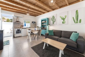 Eine moderne Küche mit Essbereich, einer Couch und Wandkunst mit Kakteenmotiven.