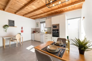 A modern kitchen with white cabinets, a built-in oven, and a dining area with a table set for two. - Apartamento Alma 2 by Escape Home (Tías)