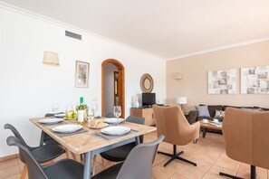 A dining area with a table set for four, a television, and a sofa in the background. - Villa Conchita by Escape Home (Torre Solí Nou)