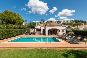 A pool area with a clear blue pool, lounge chairs, and a patio with a table and chairs. - Villa Juanita by Escape Home (Torre Solí Nou)