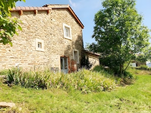 A stone building with a sloped roof, a door, and a window.