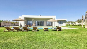 A modern house with a swimming pool, surrounded by a lawn with lounge chairs and umbrellas. - Villa Koeur - Private pool & garden not overlooked (Marrakech)