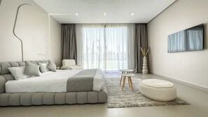 A modern bedroom with a large bed, a bedside table, a chair, and a TV on the wall. - Villa Koeur - Private pool & garden not overlooked (Marrakech)