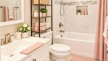A bathroom with a white sink, a toilet, a shower, and a vanity with a mirror.