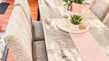 Una mesa de comedor con tapa de mármol, rodeada de sillas con cojines y tela texturizada.