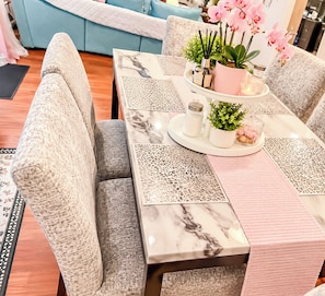 A dining table with a marble top, surrounded by cushioned chairs with a textured fabric. - Mandale Ct - Two-Story Shared Home (Fort Washington)
