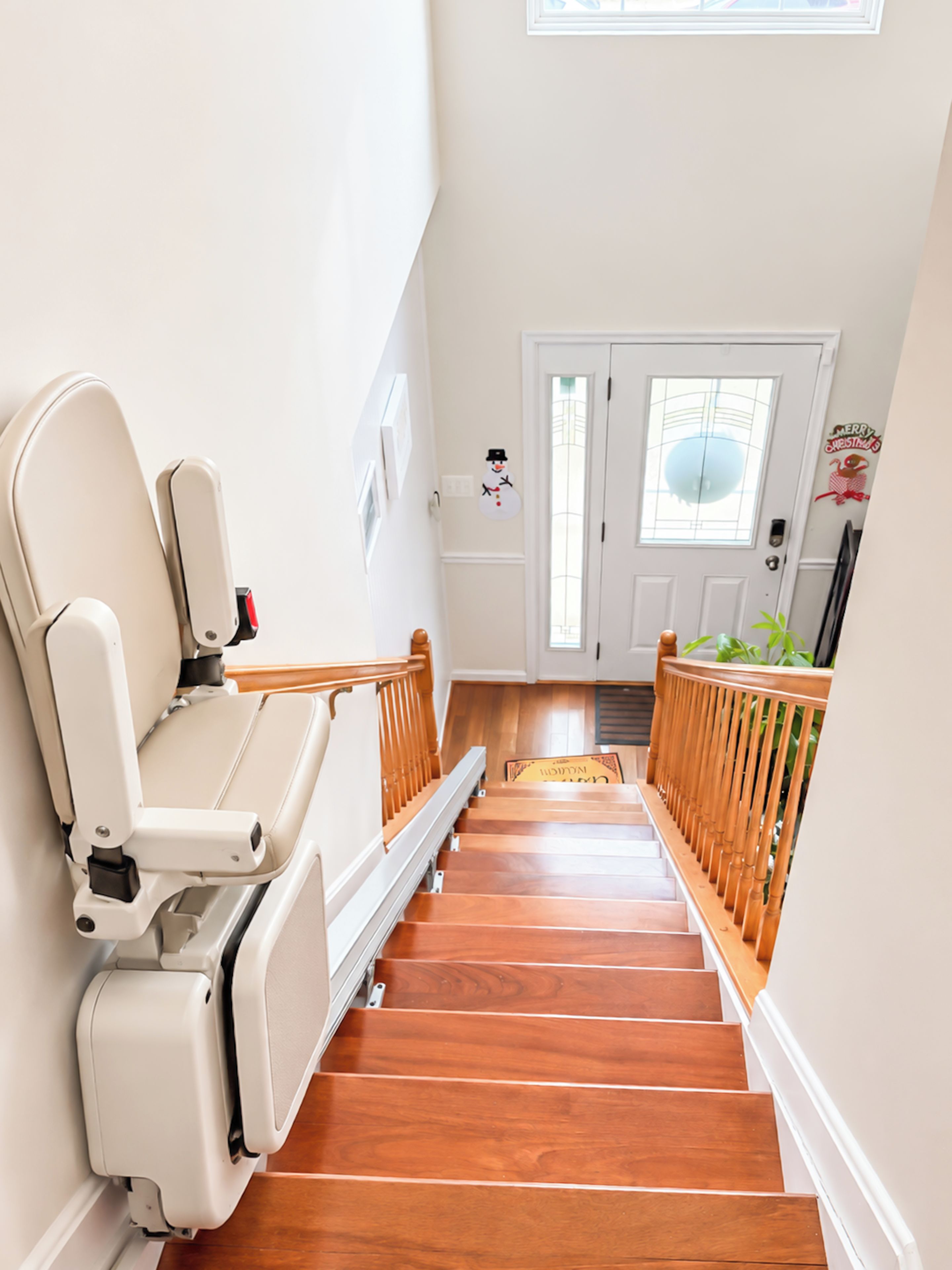 A wooden staircase with a handrail, a door with a window, and a wall-mounted decoration.