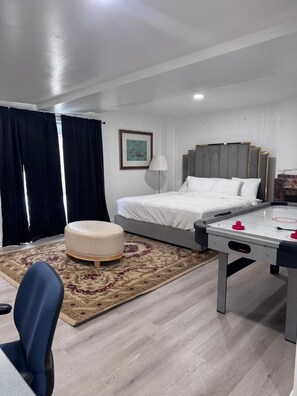 Ein modernes Hotelzimmer mit Bett, Schreibtisch, Stuhl, Teppich und einem Bild an der Wand.