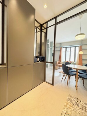 Un interior modern amb zona de menjador, cuina amb forn integrat i una finestra gran amb cortines.