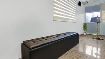 Un interior moderno con un banco, una planta en maceta y un piso de mármol.