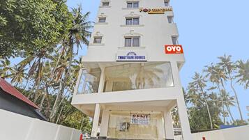 Un edificio de varios pisos con un letrero 'THRITVAM HOMES', un letrero que dice 'ALQUILER' y un letrero 'OYO ROOMS'.