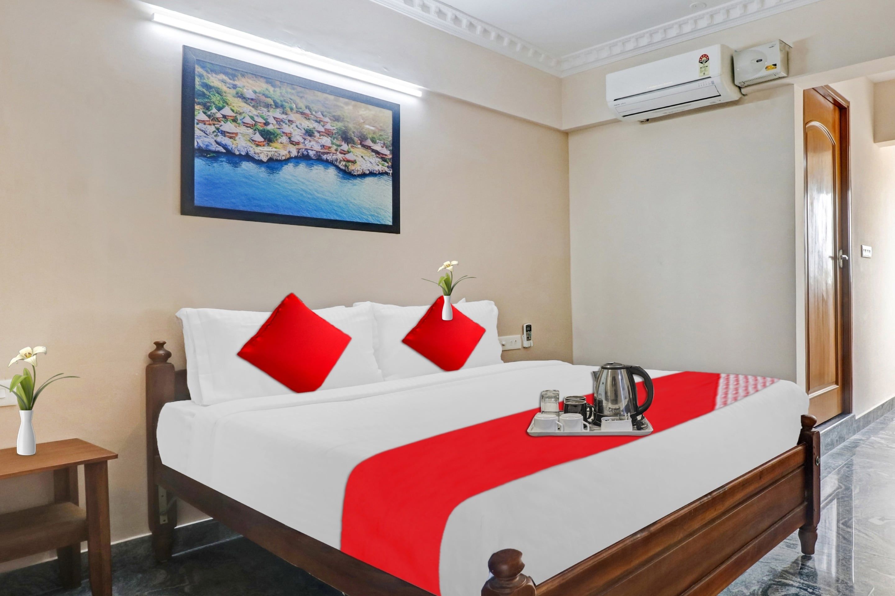 Une chambre d’hôtel avec un lit, un tableau au mur, un appareil de climatisation et un plateau avec une bouilloire et des tasses.