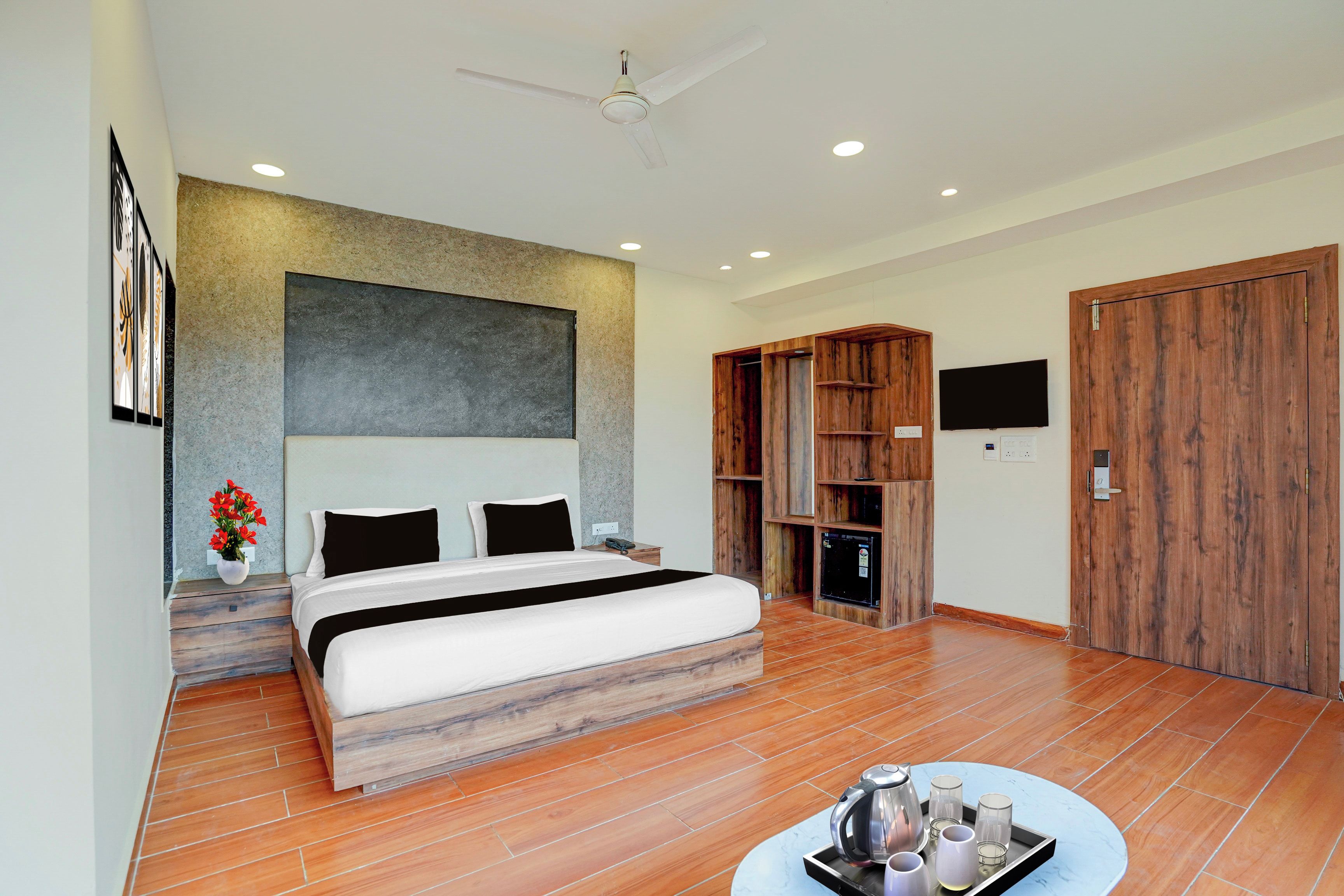 A modern bedroom with a large bed, a ceiling fan, and a wooden wardrobe.