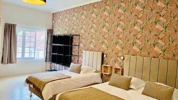 A hotel room with two beds, a large window, and a patterned wallpaper.