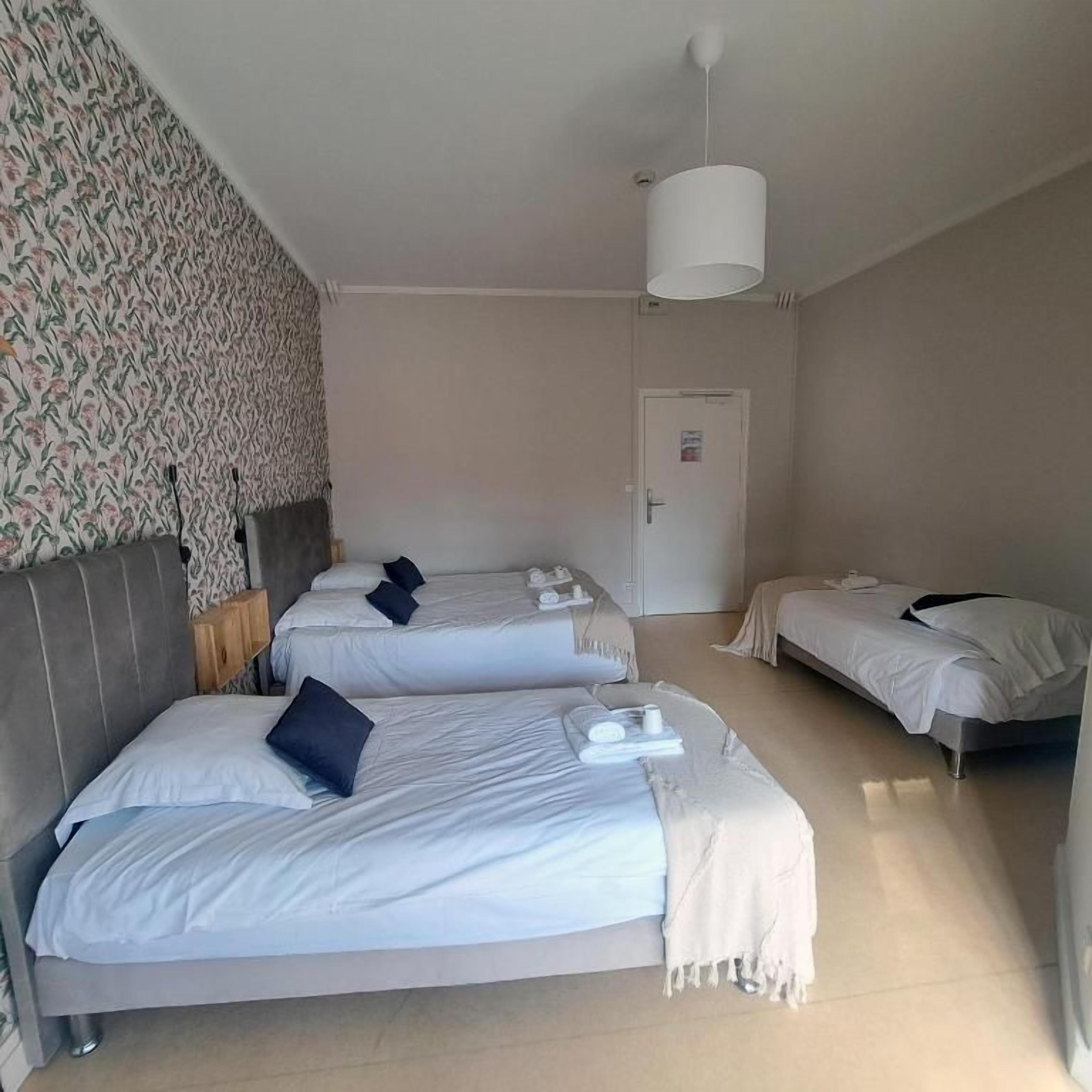 Een hotelkamer met twee bedden, een kledingkast, een deur en behang met een patroon.