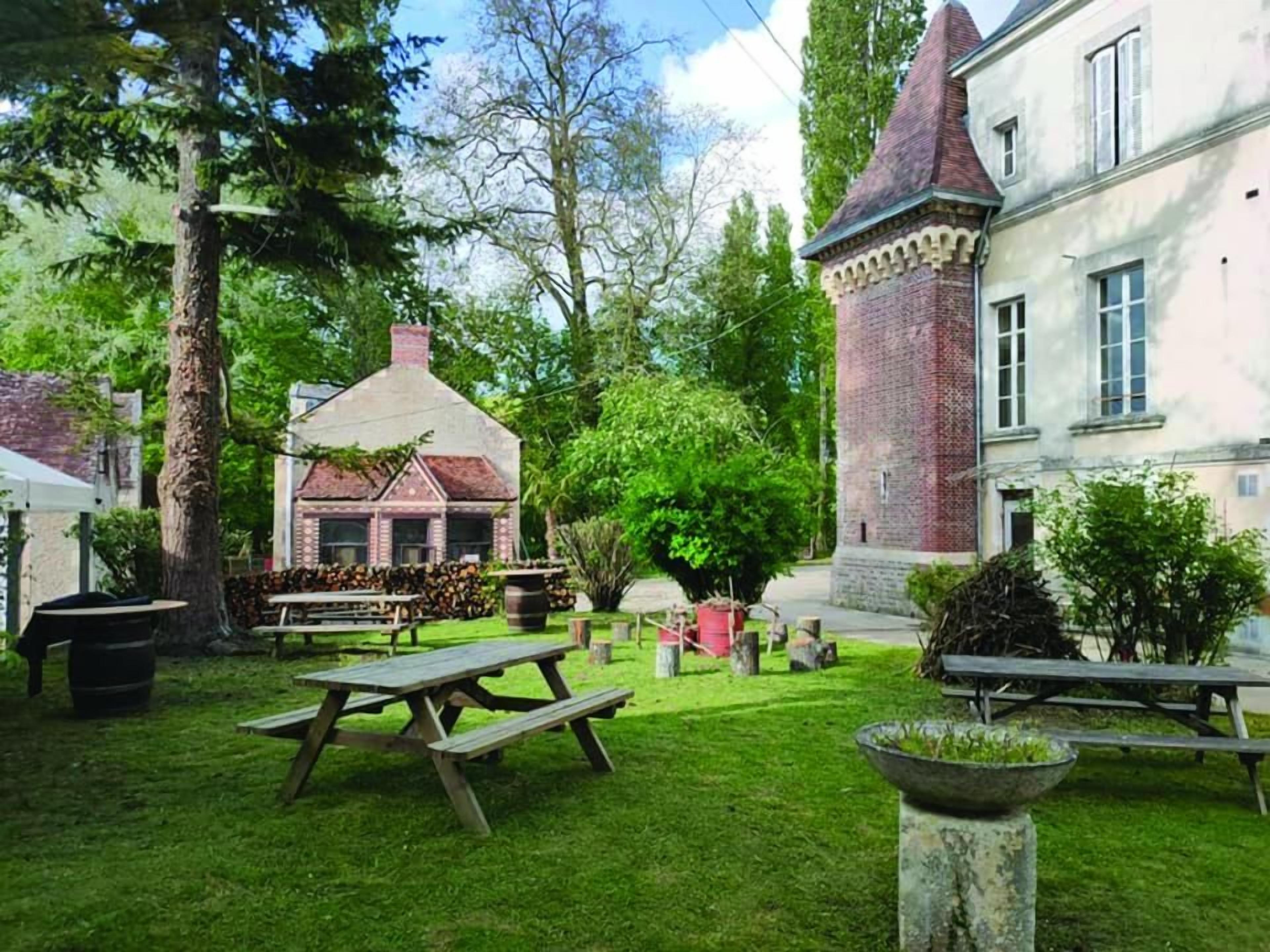 A courtyard with a picnic table, a brick tower, and a building with a pitched roof.