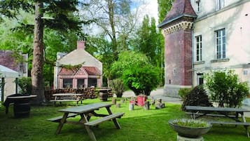 A courtyard with a picnic table, a brick tower, and a building with a pitched roof.