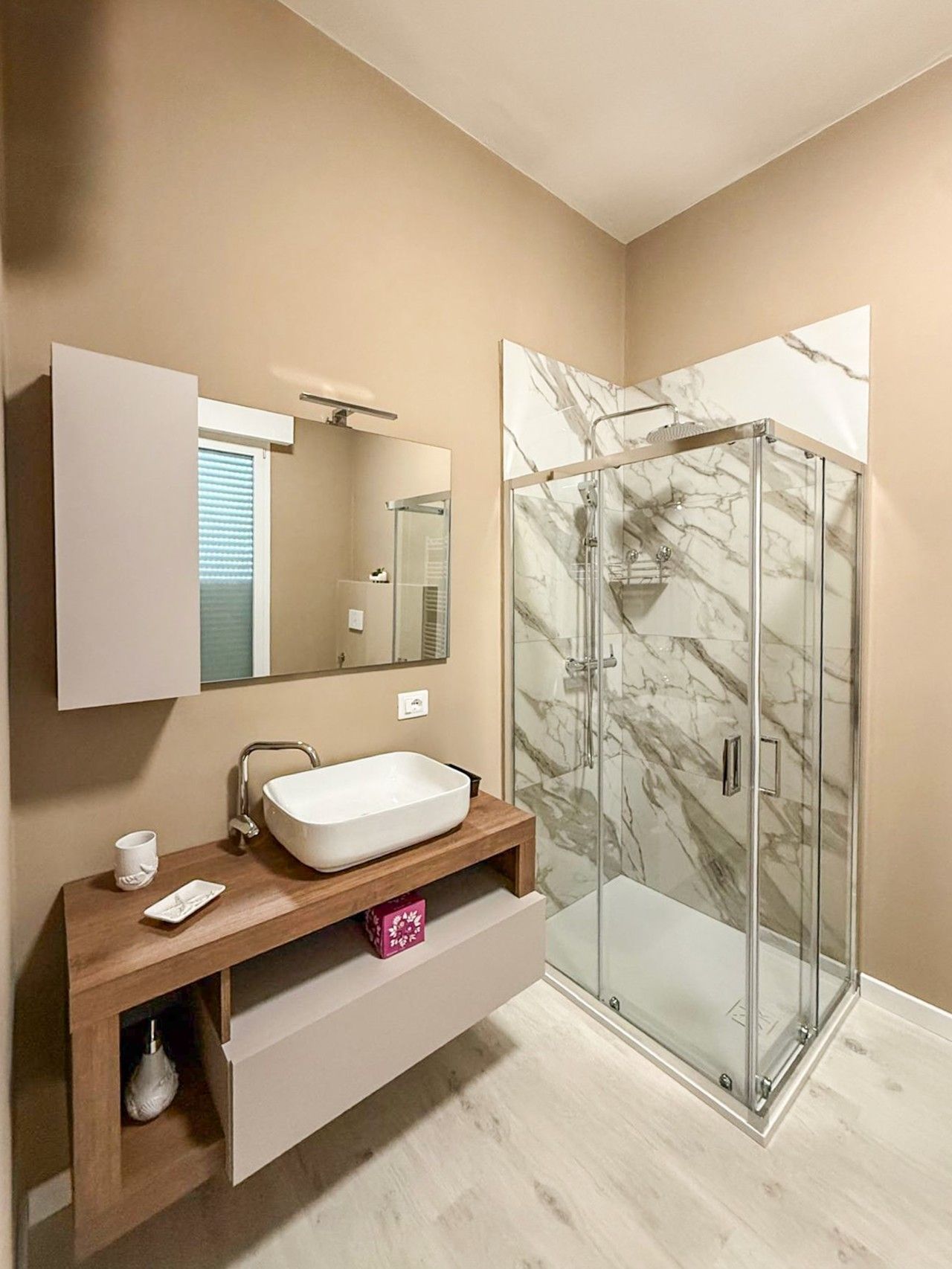 Een moderne badkamer met een glazen douchecabine, een witte wastafel en een wastafelmeubel met opbergruimte.