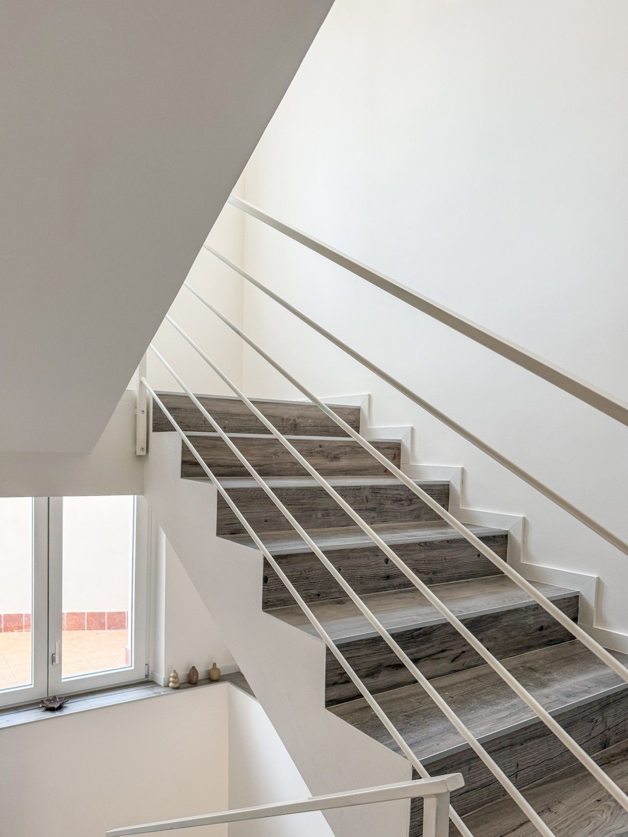 A modern staircase with white railings and wooden steps.