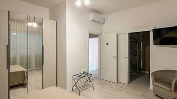 A hotel room with a bed, a chair, a small table, a TV, and a wardrobe.