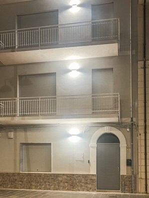 Un edificio de varios pisos con balcones, una puerta y una base de piedra.
