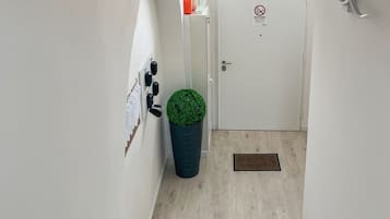 A narrow hallway with a wooden staircase leading to a door with a window.