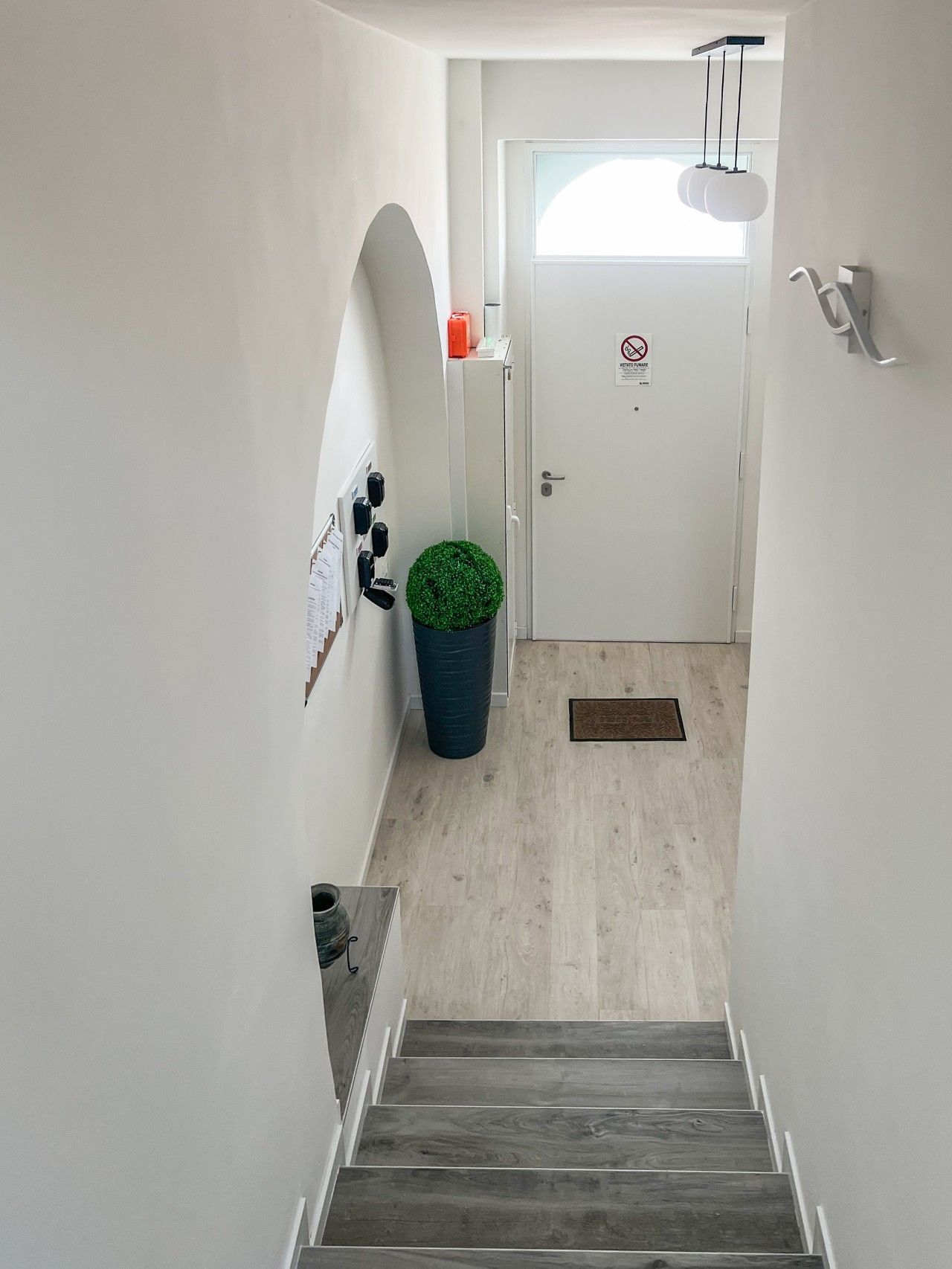 A narrow hallway with a wooden staircase leading to a door with a window.
