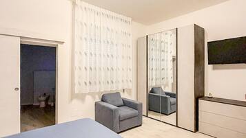 Un dormitorio con cama, una silla, cómoda y espejo.
