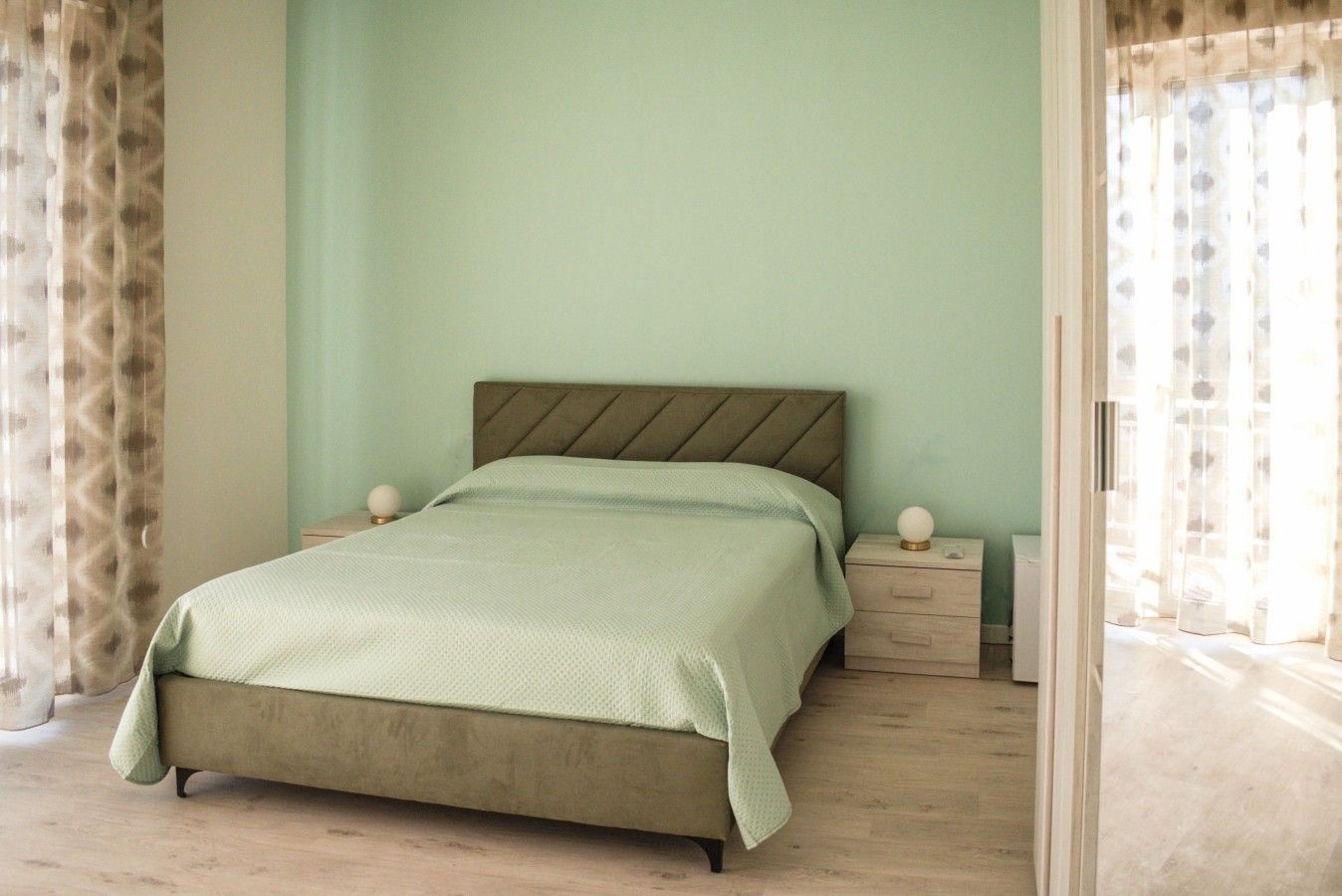 Un lit simple avec une tête de lit, deux tables de chevet et un plancher de couleur claire.