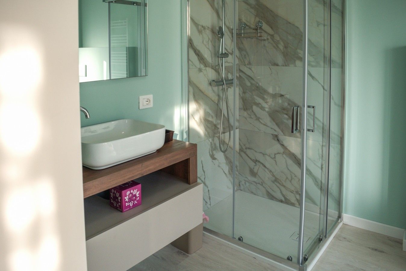 Une salle de bain avec une douche à parois de verre, un lavabo blanc et un pare-baignoire en marbre.