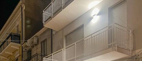 Un immeuble à plusieurs étages doté de balcons, d’une façade en pierre et d’une porte avec une fenêtre.