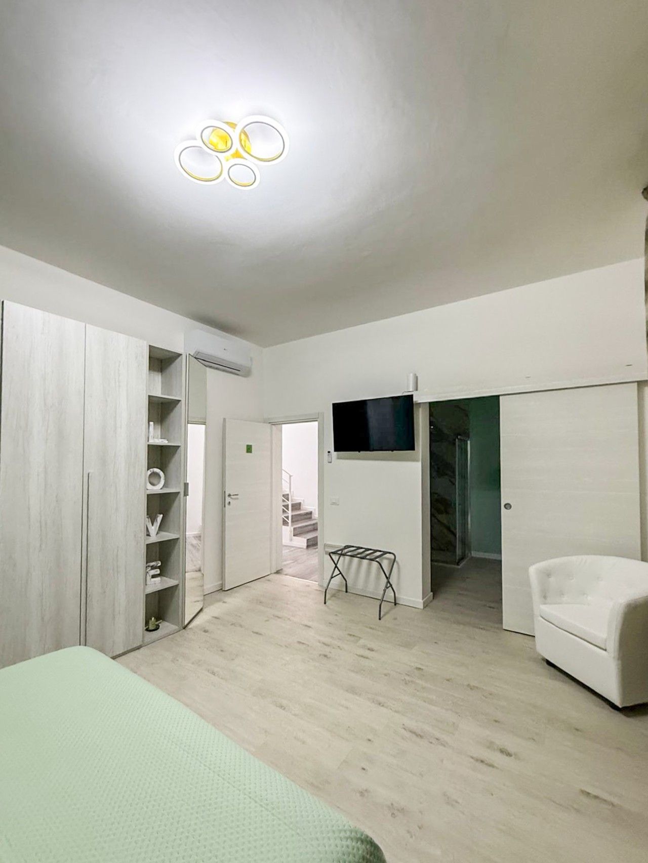 Una habitación con cama, armario, televisor y una silla.
