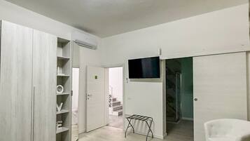 Una habitación con cama, armario, televisor y una silla.