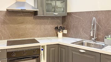 Una cocina con horno integrado, pileta de acero inoxidable y extractor.