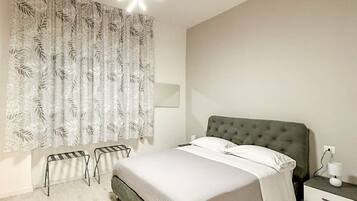 A bedroom with a bed, bedside table, lamp, and a window with curtains.