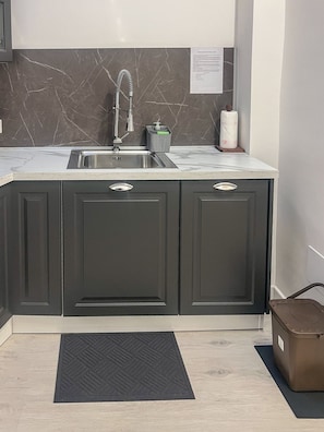 Cozinha com armários escuros, pia de aço inoxidável e backsplash de mármore.